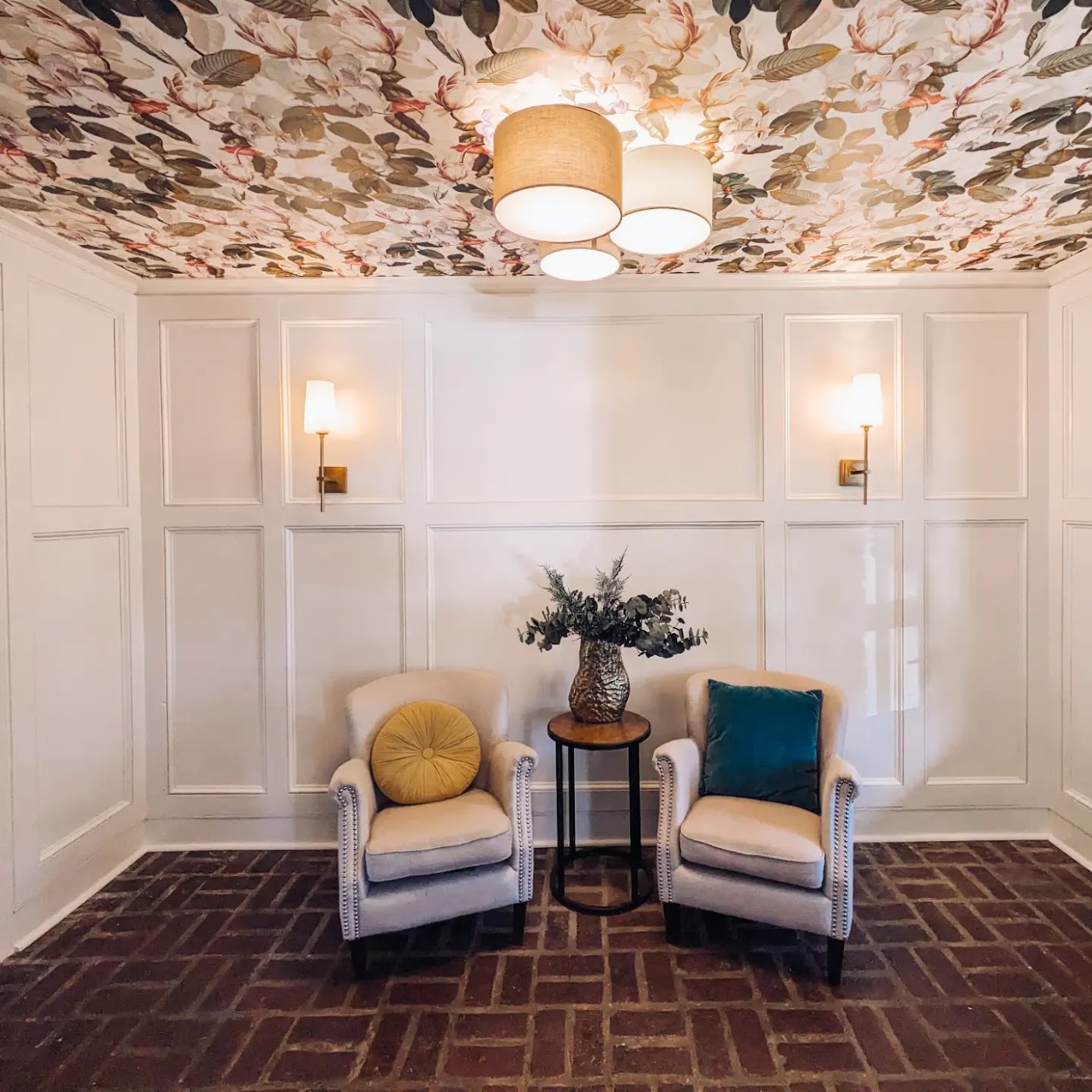 A finished sitting room with white paneled walls, a papered ceiling and layered textiles by A2Z Interiors